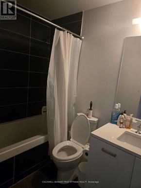 Ottawa condo for rent - A white toilet with a white shower curtain in a bathroom.