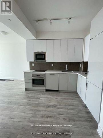 Vaughan (Concord) condo for rent - A kitchen with white cabinets and a microwave on top of the oven.