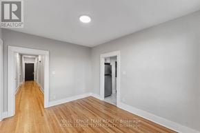 Ottawa apartment for rent - A spacious room with wooden floors and white walls, with a doorway leading to another room.
