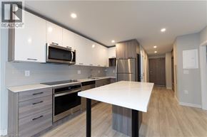 Hamilton condo for rent - A modern kitchen with a white table and stainless steel appliances.