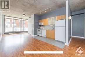 Ottawa condo for rent - A large, empty room with a kitchenette and a window.