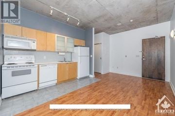 Ottawa condo for rent - A kitchen with white appliances and wooden cabinets is on the market.