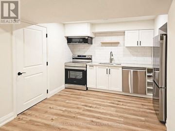St. Catharines (Haig) apartment for rent - A kitchen with white cabinets and a wooden floor.