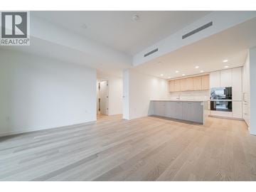 West Vancouver apartment for rent - A spacious living room with a television and a kitchen area in the background.