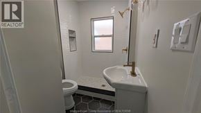 Windsor apartment for rent - A small bathroom with a toilet, sink, and mirror.