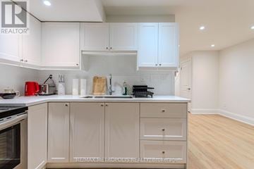 Toronto (Long Branch) apartment for rent - A kitchen with white cabinets and a wooden cutting board on the counter.