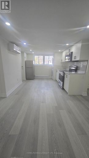 Oshawa (Donevan) apartment for rent - A spacious kitchen with white cabinets and a grey floor.