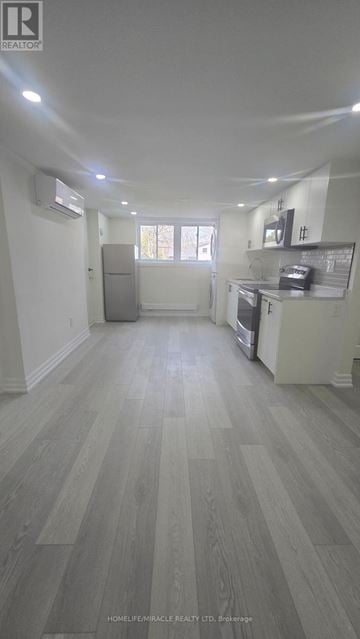 Oshawa (Donevan) apartment for rent - A spacious kitchen with white cabinets and a grey floor.