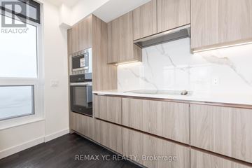 Toronto (Waterfront Communities) condo for rent - A modern kitchen with wooden cabinets and a marble backsplash.