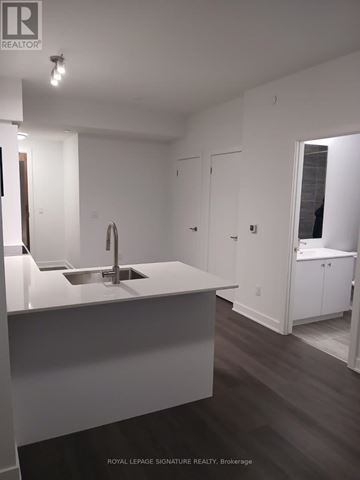 Kitchener condo for rent - A white kitchen with a sink and a brokerage sign.
