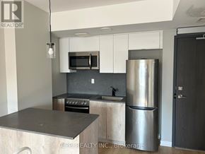 Oshawa (Central) condo for rent - A modern kitchen with a stainless steel refrigerator and microwave above the stove.