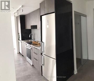 Toronto (Church-Yonge Corridor) condo for rent - A kitchen with a black refrigerator and white cabinets.