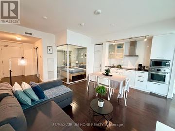 Toronto (Waterfront Communities) condo for rent - A modern living room with a grey couch and a glass wall.
