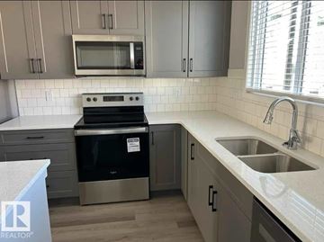 Edmonton townhouse for rent - A kitchen with a stove, microwave, and sink.