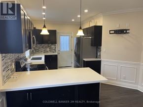 Oshawa (O'neill) duplex for rent - A kitchen with a white counter top and black cabinets.