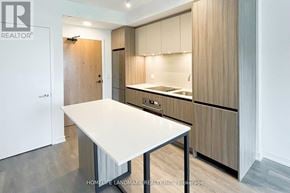 Vaughan (Beverley Glen) condo for rent - A modern kitchen with a white table and wooden cabinets.