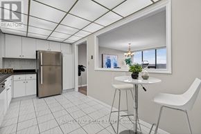 Hamilton (Stoney Creek) condo for rent - A kitchen with a refrigerator, a dining table with two chairs, and a window with a view of the outdoors.