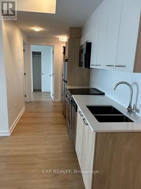 Ottawa apartment for rent - A kitchen with wooden floors and white cabinets.