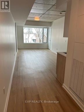 Ottawa apartment for rent - A long, empty hallway with wood floors and white walls.