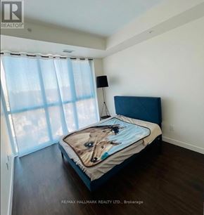 Waterloo condo for rent - A bedroom with a bed, a window with curtains, and a lamp.
