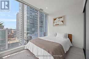 Toronto (Waterfront Communities) condo for rent - A bedroom with a large bed and a view of the city.