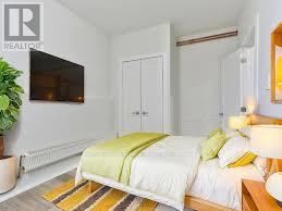 Toronto (Wychwood) multi-family for rent - A bedroom with a bed, a plant, and a television.