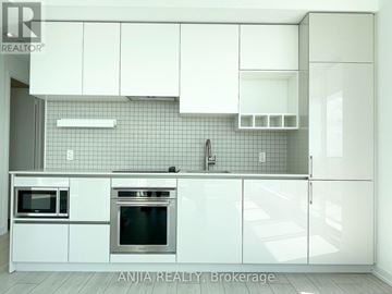 Vaughan (Vaughan Corporate Centre) condo for rent - A modern kitchen with white cabinets and appliances.