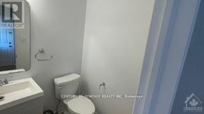 Ottawa townhouse for rent - A white toilet in a bathroom with a sink and mirror.