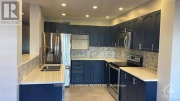 Ottawa townhouse for rent - A kitchen with dark blue cabinets and a stainless steel refrigerator.