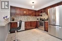 Mississauga (Central Erin Mills) townhouse for rent - A kitchen with wooden cabinets and a stone backsplash.
