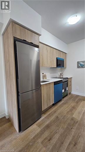 Kitchener apartment for rent - A kitchen with a stainless steel refrigerator and wooden cabinets.