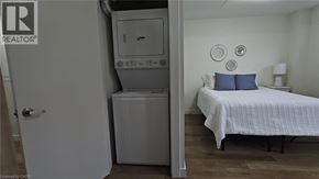 Kitchener apartment for rent - A bedroom with a bed, pillows, and a washing machine.
