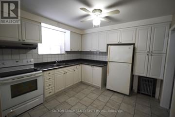 Toronto (Oakwood Village) multi-family for rent - A kitchen with white cabinets and a black countertop.