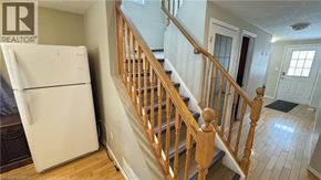 Waterloo townhouse for rent - A white fridge in a room with a wooden staircase.