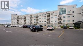 Windsor condo for rent - A parking lot in front of a large white building with the logo REALTOR on it.