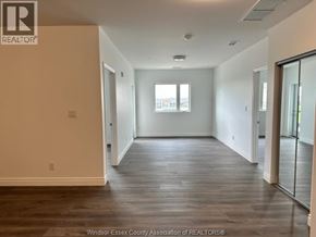 Windsor condo for rent - A spacious room with wooden floors and a large window.