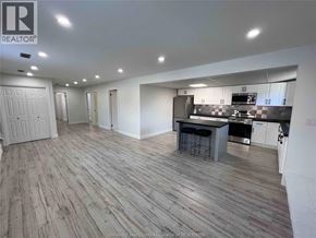 Tecumseh apartment for rent - A spacious kitchen and dining area with wooden flooring and white walls.