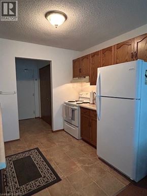 Listowel apartment for rent - A kitchen with a white refrigerator and a washer and dryer unit.