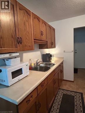 Listowel apartment for rent - A kitchen with wooden cabinets and a white microwave on the counter.