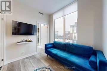 Toronto (Clanton Park) condo for rent - A living room with a blue couch and a flat screen TV mounted on the wall.