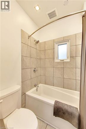 Sarnia apartment for rent - A white bathroom with a toilet, tub, and shower.