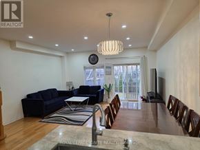 Mississauga (Churchill Meadows) townhouse for rent - A spacious living room with a dark blue sofa and a wooden dining table.