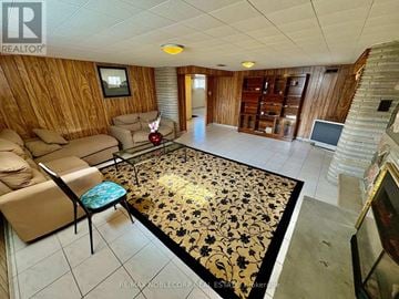 Toronto (Downsview-Roding-Cfb) apartment for rent - A living room with a wooden wall and a rug with black and gold designs.