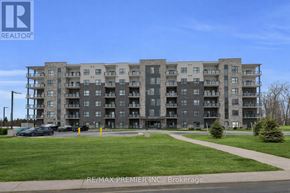 Kitchener condo for rent - A large apartment complex with a parking lot in front.