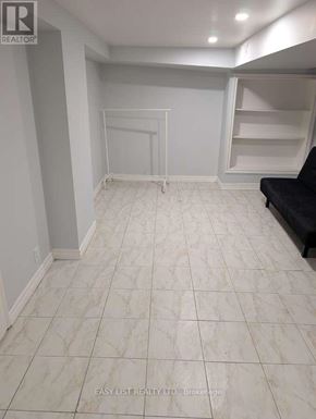 Toronto (Newtonbrook West) apartment for rent - A spacious room with white tiled flooring and a black couch.