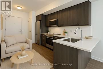 Clarington (Bowmanville) condo for rent - A modern kitchen with a sink, refrigerator, and cabinets.