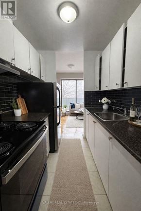 Toronto (Wexford-Maryvale) condo for rent - A modern kitchen with black appliances and white cabinets.