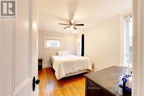 Sarnia apartment for rent - A bedroom with a bed, a ceiling fan, and a window.