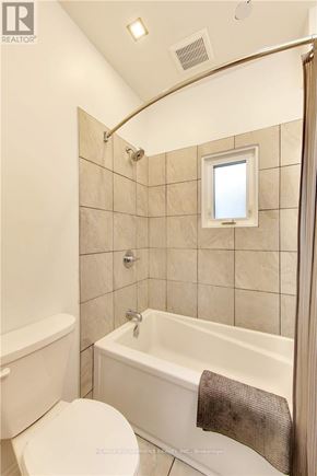 Sarnia apartment for rent - A white toilet sits next to a white bathtub in a bathroom.