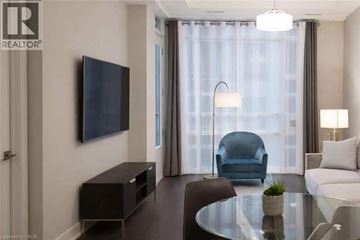 Hamilton condo for rent - A modern living room with a black television and a blue chair.